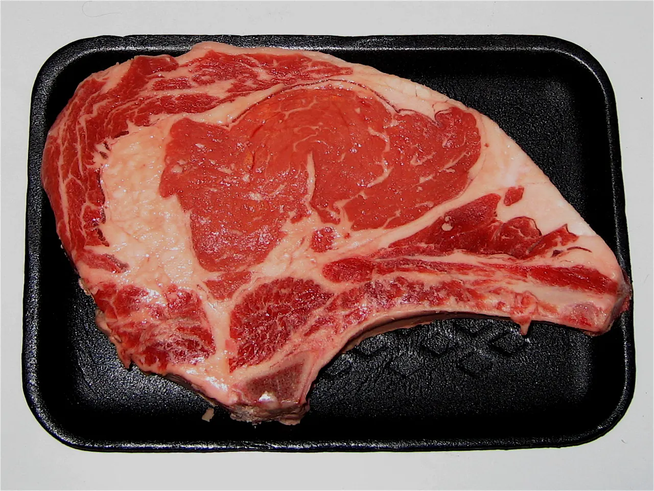 USDA Choice bone-in rib steak with visible marbling on a cutting board
