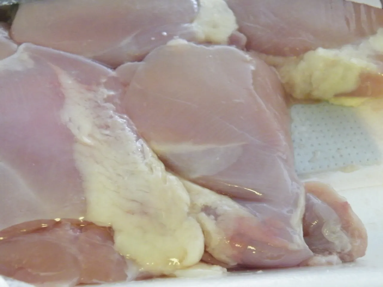Raw bone-in chicken thighs with skin on a tray