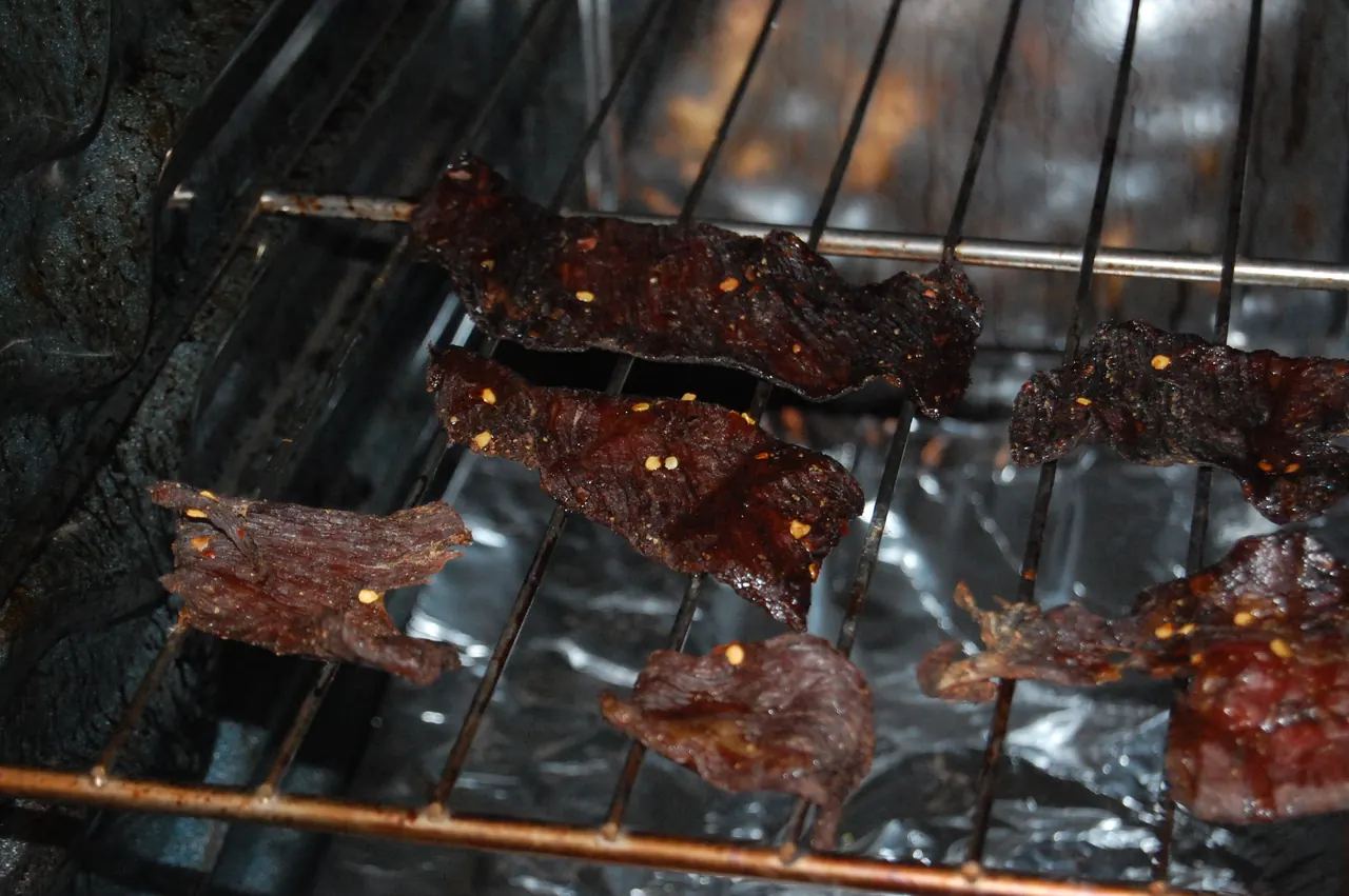 Beef jerky strips drying on racks partway through the process
