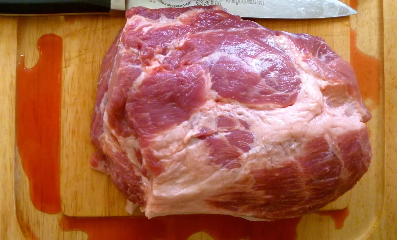 Raw pork shoulder coppa cut showing marbling and muscle seams